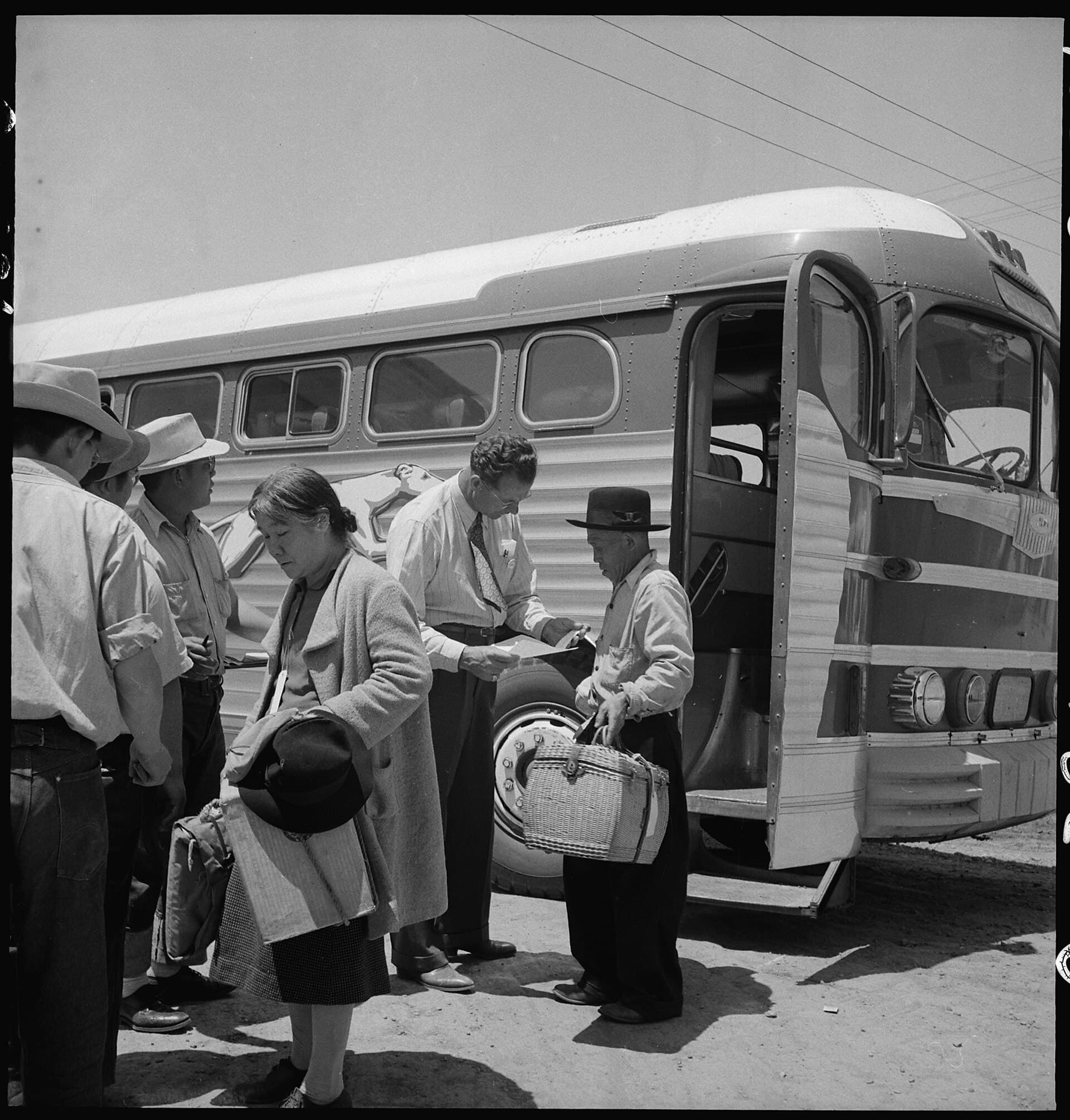 Japanese American families from the Lodi grape-growing district waiting near a bus in Stockton in 1942